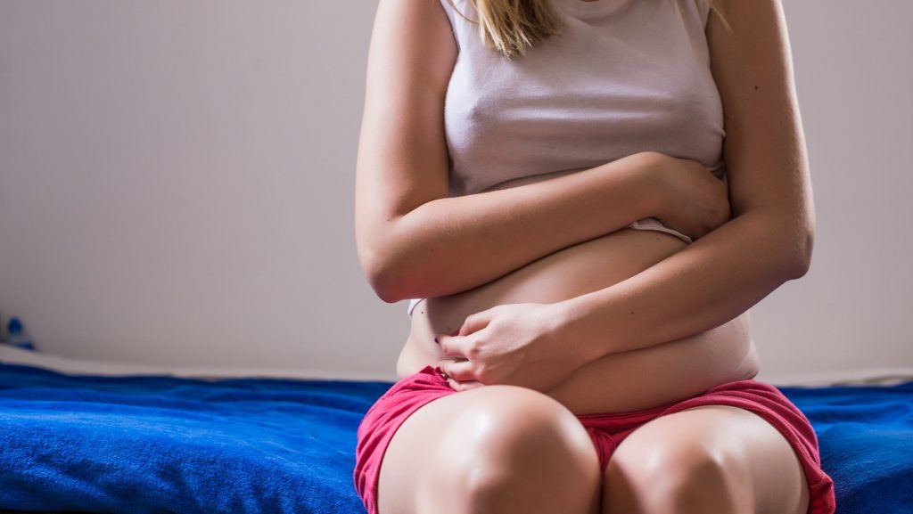 Woman with her monthly menstrual pains clutching her stomach wit